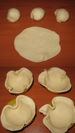 Подошедшее тесто обмять, разделить на одинаковые части размером с перепелиное яйцо (я обычно делю на 12-15 частей). Каждую часть теста на присыпанной мукой поверхности раскатать в круг, выстелить им формочки для кексов (у меня силиконовые, если у вас железные формочки, тогда вначале немного смажьте их маслом, а затем выкладывайте тесто) так, чтобы немного края свисали.