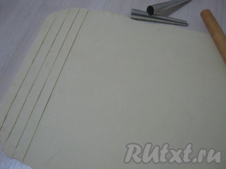 Из этого количества ингредиентов получается примерно 40-45 трубочек из слоеного теста с кремом. Слоёное тесто раскатываем в пласт толщиной 2-3 мм. Нарезаем тесто полосками шириной 2 см и длиной примерно 30-35 см.