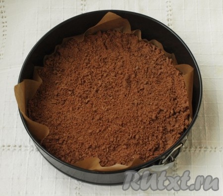 К получившейся масляной массе добавляем муку, какао и тщательно перетираем руками до получения мелкой, однородной шоколадной ("торфяной") кроши. Половину получившейся шоколадной крошки выкладываем в разъёмную форму для выпечки (у меня форма диаметром 24 сантиметра), застеленную пекарской бумагой.