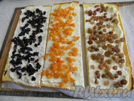 Развернуть бисквит, снять пергамент, намазать на него 2/3 крема.
Корж разрезать на 3 полоски, на каждую из них разложить определенный вид сухофруктов.