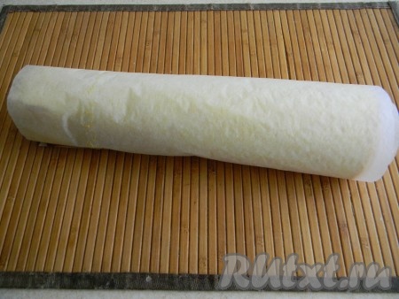 Корж слегка охладить (до теплого), накрыть листом пергамента и аккуратно снять нижний лист. Затем вернуть бумагу на место и свернуть корж вместе с пергаментом в рулет.