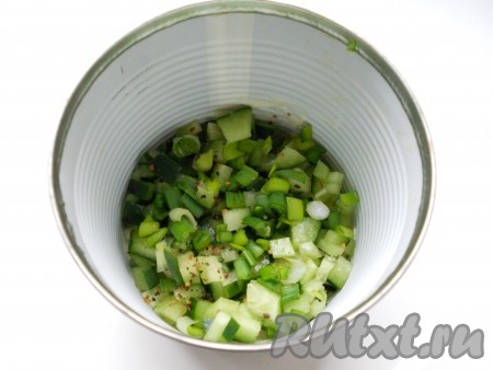 Второй слой - порезанные мелким кубиком свежие огурцы и измельченный зеленый лук. Посолить немного и поперчить.
