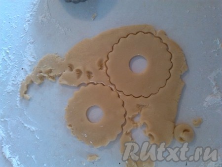 Сливочное масло должно быть комнатной температуры, поэтому достать его нужно заранее, постепенно оно согреется и станет достаточно мягким. Яйца разбиваем в миску и взбиваем вручную (или миксером) до побеления. Затем добавляем мягкое сливочное масло вместе с сахаром и ванильным сахаром, взбиваем венчиком (или миксером) до однородной массы. Всыпаем соль и разрыхлитель, частями добавляем просеянную муку, замешивая не липнущее к рукам песочное тесто. Вымешиваем его не более 1-2 минут - чем меньше, тем лучше, так как при вымешивании песочного теста выбивается весь кислород и выпечка из него получится твёрдой и жёсткой. На присыпанной мукой поверхности раскатываем тесто скалкой до толщины 5-6 миллиметров, фигурной выемкой вырезаем кольца.