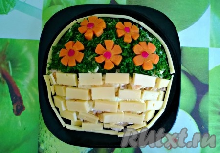 5. Для украшения салата зелень промойте и мелко нарежьте. 
Верхнюю часть круга посыпьте нарезанной зеленью. Из отварной моркови вырежьте цветы и украсьте ими. Для корзинки сыр нарежьте тонкими ломтиками и аккуратно выкладывайте в ряд. 