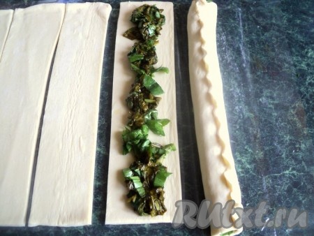 По центру полосок выложить начинку из щавеля и защипнуть края, формируя длинную трубочку.