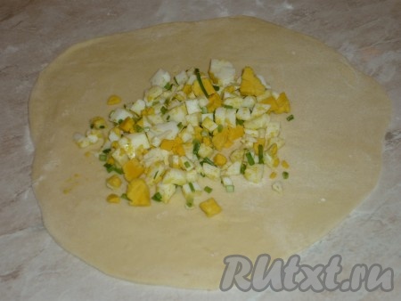 Затем тесто разделить на небольшие кусочки и на присыпанной мукой поверхности раскатать в тонкие лепёшки круглой формы. В середину каждой раскатанной лепёшки выложить примерно по 1,5 столовых ложи начинки из яйца и лука.