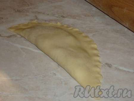 Затем сложить лепёшку пополам. Обрезать лишние куски, образуя полукруг. Хорошо прижать края чебурека, можно это сделать вилкой или руками.