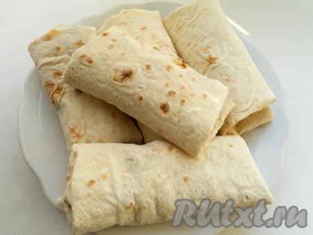 Края лаваша подогнуть и свернуть рулетом. Таким образом подготовить все рулетики.