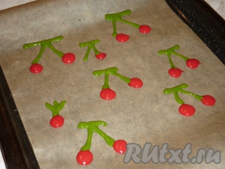 Противень застелить пергаментом. В пакетиках с цветным тестом сделать небольшие дырочки. И нарисовать вишни с веточками и листочками. Отправить противень с вишнями на 2-3 минуты в холодильник.