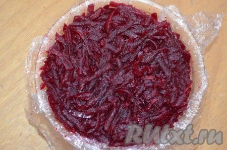 Завершающим слоем салата "Сёмга на шубе" станет свекла, натёртая на крупной тёрке, утрамбовать. Аккуратно накрыть слой свеклы пищевой плёнкой, свисающей с краёв формы.