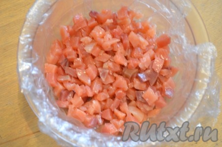 Слабосолёную сёмгу нарезать на мелкие кубики. Дно и бока подходящей миски застелить пищевой плёнкой так, чтобы плёнка свисала с краёв формы. Мы будем формировать салат-перевёртыш, то есть в дальнейшем он будет переворачиваться на тарелку, благодаря плёнке это сделать будет достаточно просто. В застеленную форму выложить рыбу первым слоем.