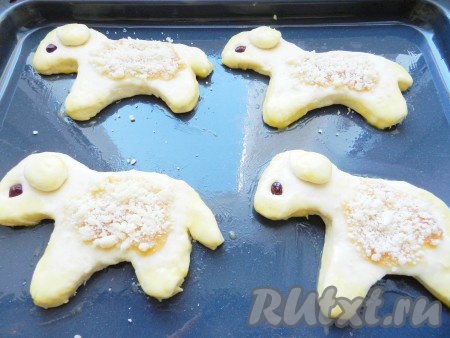 Посередине фигурки нанести персиковый (или другой) джем, посыпать сверху штрейзелем. Уши, мордочку, лапы и хвост смазать желтком. Оставить подходить еще 20 минут. Духовку разогреть до 190 градусов и выпекать пасхальных барашков в течение 20-25 минут.