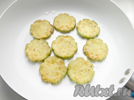 В сковороде разогреть растительное масло. Выложить несколько кружочков кабачка в один слой, обжарить на среднем огне до румяной корочки с двух сторон. Жареные кабачки со сковороды выкладывать на бумажные полотенца, чтобы убрать лишнее масло. Постепенно обжарить все кабачки.