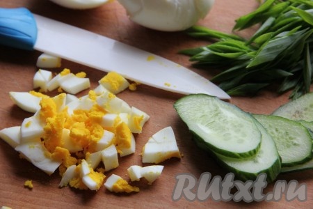 Яйца отварить и нарезать кубиками, огурцы - ломтиками. Зеленый лук измельчить.
