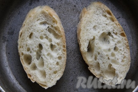 Багет подсушить на сухой сковороде с одной стороны. Подсушенную сторону багета натереть чесноком.
