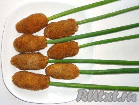 С запеченных куриных рулетиков убрать маленькие деревянные шпажки. Длинные деревянные шпажки оформить луком и затем прикрепить рулетики.
