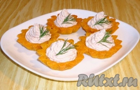 С помощью кондитерского шприца или мешка с насадкой "звёздочка" заполнить охлаждённые кукурузные тарталетки паштетом из крабовых палочек и украсить зеленью.
