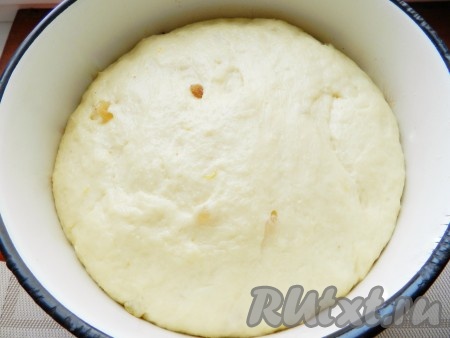 Замешанное тесто поместить в миску, накрыть чистым полотенцем и убрать для подхода в тёплое место без сквозняков. Я обычно включаю в духовке свет и убираю туда миску с тестом. Тепла от лампочки достаточно, чтобы тесто хорошо подошло. Для подъёма теста понадобится 1-1,5 часа. Пока тесто поднимается, нужно изюм промыть водой, выложить в небольшую ёмкость, залить кипящей водой, оставить минут на 5, затем воду слить. Обсушить изюм, разложив его на полотенце. Лимон тщательно вымыть, обсушить, снять с него жёлтую цедру, не затрагивая, находящийся под ней белый слой. Поднявшееся тесто обмять, добавить в него лимонную цедру и обсушенный изюм. Снова вымесить, чтобы изюм и цедра равномерно распределились, и убрать в тёплое место на 30 минут.