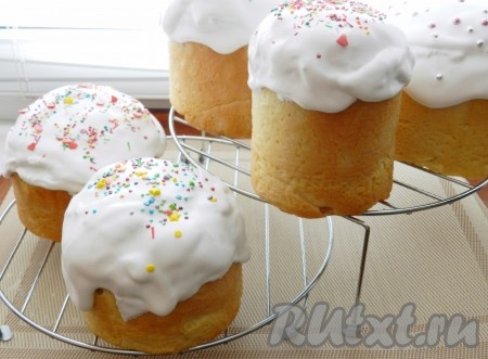 Готовые куличи с орехами и изюмом (я испекла 5 штук) достать из духовки, дать немного остыть, вынуть из форм, поставить на решётку. Для приготовления глазури миксером взбить холодные яичные белки с лимонным соком и сахарной пудрой до устойчивых пиков. Покрыть тёплые куличи глазурью, посыпать кулинарной посыпкой.