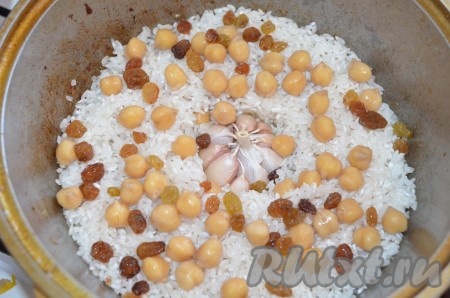 Нут заранее отварить почти до готовности. Для этого заливаем горох холодной водой, ставим на сильный огонь, даем закипеть, затем делаем минимальный огонь и варим. Через 1 час нужно его попробовать, если мягкий, огонь выключить.&nbsp;Рис и изюм промыть. На мясо уложить слой риса ровно. На рис нут и изюм. Посолить (0,5 чайной ложки соли), добавить чеснок целой головкой.