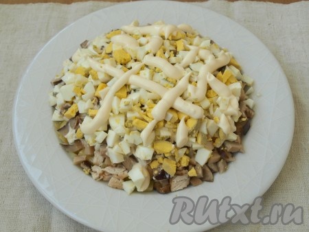 Нарезать кубиками яйца, выложить слоем поверх грибов, посолить и поперчить, сделать майонезную сеточку.&nbsp;
