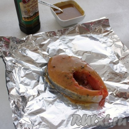 Взять кусок фольги, сложить его в 2 слоя. Часть фольги, на которую будет выкладываться форель, смазать растительным маслом, выложить стейк форели, хорошо смазанный медово-горчичным соусом.