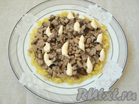 Нарезать кубиками грибы, выложить вторым слоем. Нанести снова майонез.