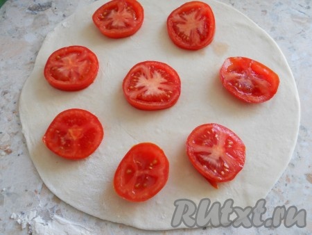 "Отдохнувшее" тесто разделить на 2 части, раскатать каждую в круглую тонкую лепешку. Помидоры порезать кружками (каждый помидор - 3-4 кружка). Разложить кружочки на лепешке на расстоянии друг от друга 2-3 см.
