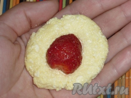 Клубнику моем, удаляя чашелистики, обсушиваем ягоды. Если ягоды крупные, их можно разрезать на 2 части. По истечении 2 часов берём понемногу творожную массу, разминаем в лепёшку, в середину кладём клубничку и защипываем края. Получается круглый ленивый вареник с клубникой внутри. Аналогично формируем все вареники.