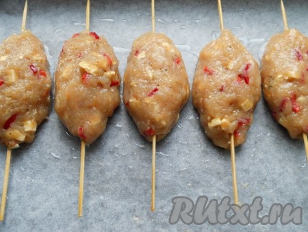 Противень застелить пергаментом (или фольгой), смазать растительным маслом. Деревянные шпажки замочить на 10 минут в воде. Из подготовленного фарша сформировать продолговатые котлеты, нанизать их на шпажки. Выложить на противень.