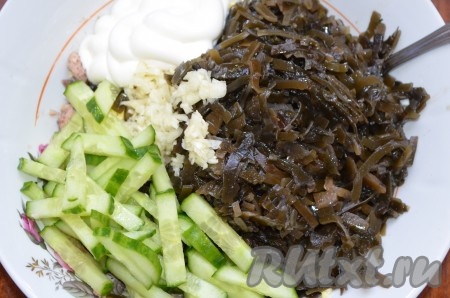 Огурец порезать соломкой, чеснок измельчить. В салат к рыбным консервам и яйцам отправить чеснок, огурец и морскую капусту. Посолить, поперчить, заправить майонезом или сметаной.
