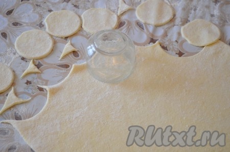Разделить тесто на 2 части. Каждую часть теста на присыпанной мукой поверхности раскатать достаточно тонко, как на пельмени. Вырезать кружочки рюмкой.