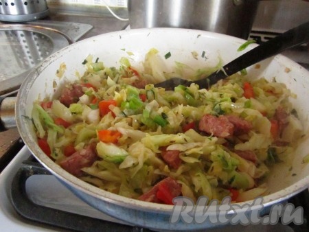 Хорошо перемешайте капусту и тушите ещё около 5-10 минут под крышкой. Вкусная молодая капуста, тушёная с копчёной колбаской, готова!