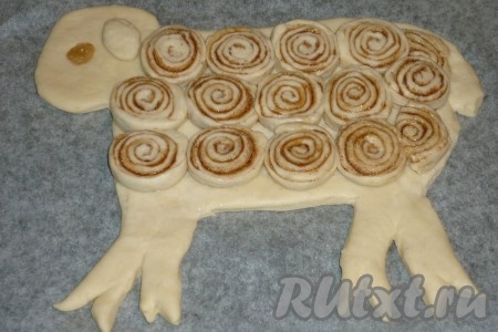 Слегка смачиваем кисточкой тело барашка водой и выкладываем сверху порезанные кусочки рулета. Из изюма делаем глазик, из небольшого кусочка теста - ушко. Оставляем барашка на 15-20 минут, чтобы тесто подошло. Затем смазываем яичным желтком. Выпекаем 30-35 минут в разогретой до 180 градусов духовке.
