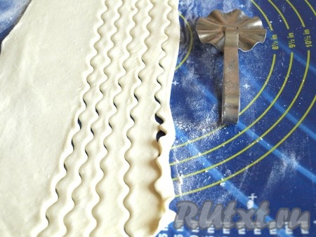 Слоёное тесто разморозить при комнатной температуре, раскатать толщиной 5 мм и нарезать на полоски шириной 7-10 мм. Нарезать можно ровно или фигурно.