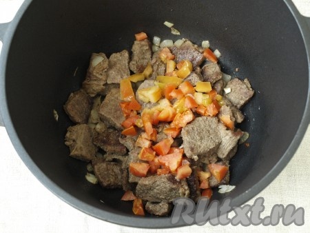 К мясу добавить нарезанный кубиками лук и помидор.