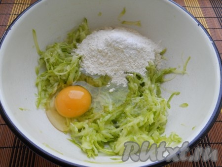 В миску с кабачковой массой добавить яйцо и 50 грамм муки, перемешать кабачковое тесто.