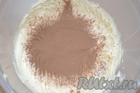 Пока бисквит остывает, взбить размягченное масло с какао-порошком.
