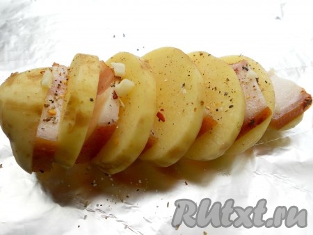 Каждую порезанную картофелину поместить на лист фольги. Каждый кусочек сала выкладывать между кружочками картофеля. Посолить хорошо (если сало соленое - не переборщите с солью), посыпать смесью перцев и порезанным мелко чесноком. Полить сверху каждую картофелину 0,5 чайной ложкой растительного масла.
