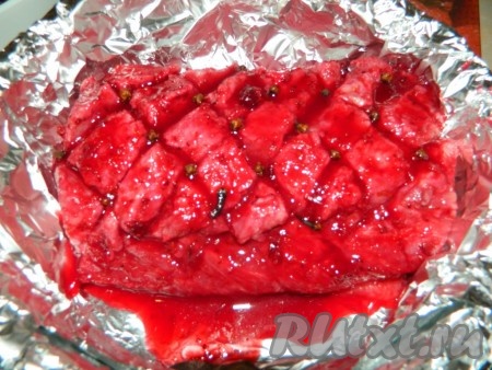 Дальше убираем ягоды клюквы с мяса. Перекладываем свинину в форму, застеленную фольгой. Вставляем по всему мясу бутоны гвоздики. Поливаем мясо соком от маринада. Заворачиваем свинину в фольгу и отправляем в разогретую духовку запекаться при температуре 180 градусов на минут 60.