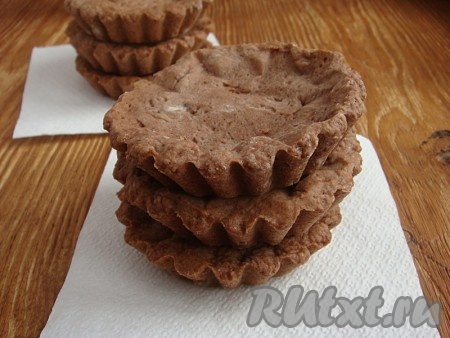 В каждую формочку на основу из теста положить кусочки бумаги для выпечки, сверху насыпать рис или фасоль. Поставить  на 15 минут в предварительно разогретую до 180 градусов духовку, затем удалить груз с бумагой и вернуть формочки в духовку еще на 10-12 минут, выпекать до готовности. Шоколадные корзинки готовы.