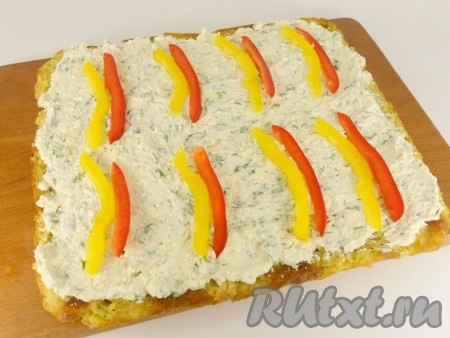 Остывший кабачковый корж смазать творожно-сырной массой. Перец болгарский порезать длинными, тонкими кусочками и выложить по 2 штуки разного цвета на расстоянии 10 см.
