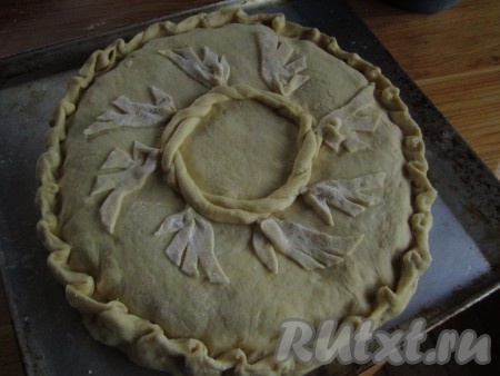От второй части теста отщипните немного и отложите для украшения пирога. Из оставшегося теста раскатайте вторую лепёшку, накройте ею пирог сверху, защипните края. Сделайте украшения для пирога из отложенного кусочка теста и украсьте пирог с щавелем на Ваше усмотрение.