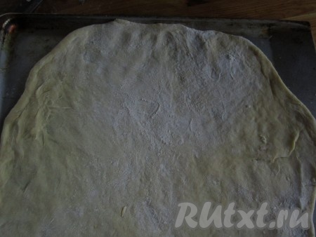 Одну половину теста раскатайте в тонкую лепёшку и переложите на смазанный маслом противень.