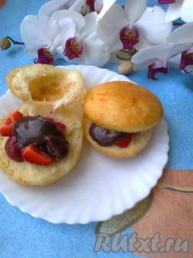 Остывшие пончики посыпать сахарной пудрой. Разрезать по средине и положить кусочки клубники, а сверху полить остывшей шоколадной глазурью.
