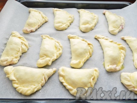 Противень застелить бумагой для выпечки, выложить на него слоеные пирожки с вишней и оставить для подъема в теплом месте на 20 минут. Смазать каждый пирожок яйцом. Поставить противень с пирожками в разогретую до 210 градусов духовку и выпекать в течение 5 минут. Затем уменьшить температуру духовки до 180 градусов и выпекать еще 20-25 минут до золотистого цвета.
