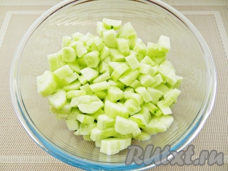 Огурцы очистить от кожицы, нарезать кубиками и выложить в салатницу.