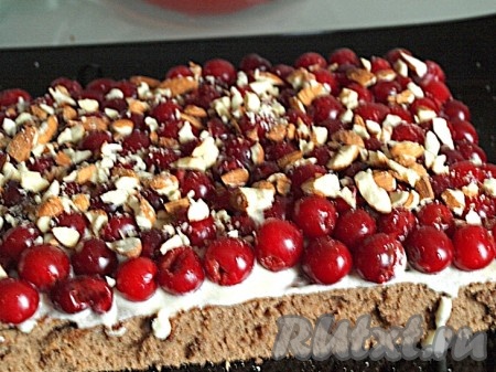 Испечённый корж разрезать пополам, сложить друг на друга и обрезать края около 1,5 см шириной, там где они слегка неровные.&nbsp;Один корж пропитать частью вишнёвого сока с коньяком, смазать кремом. Выложить вишню и рубленый миндаль.
