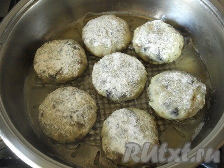 В глубокую миску всыпать примерно 1 столовую ложку муки. Обвалять картофельные котлеты с грибами в муке со всех сторон. В сковороде хорошо разогреть подсолнечное масло, выложить котлеты в сковороду и обжарить до подрумянивания снизу на среднем огне (примерно в течение 3 минут).