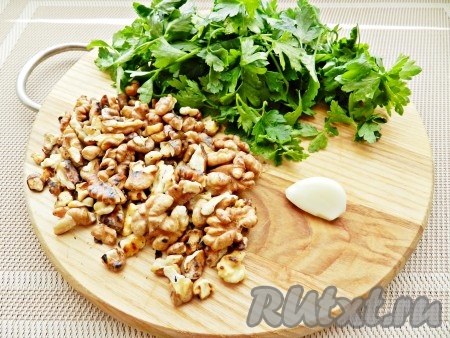 Грецкие орехи обжарить на сухой сковороде. Чеснок очистить. Петрушку вымыть, обсушить, оторвать стебли. Немного петрушки и орехов оставить для украшения.
